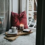 The Smart Holiday Command Center: A Calmer Way to Plan the Season Calm holiday planning moment by a window with candlelight, books, and a warm drink, reflecting a peaceful and organized season.